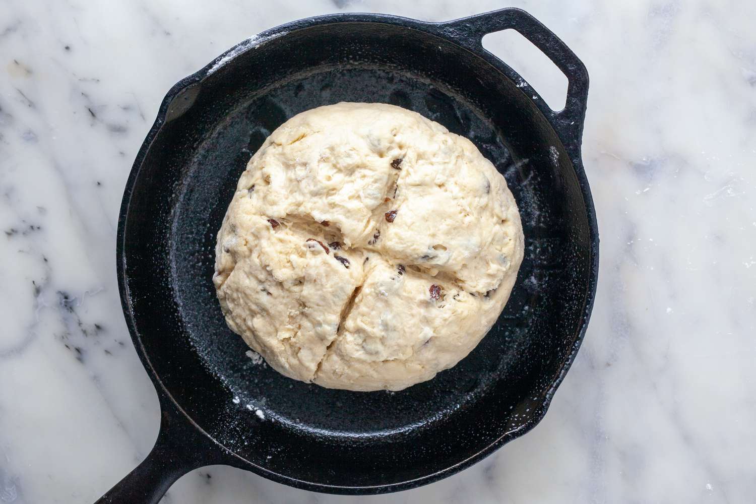 Irish Soda Bread dough in a skillet with an X cut into the center, ready to bake