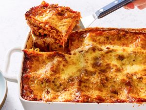 A dish of baked lasagna with a portion being lifted out using a spatula