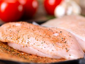Sideview of a seasoned raw chicken breast
