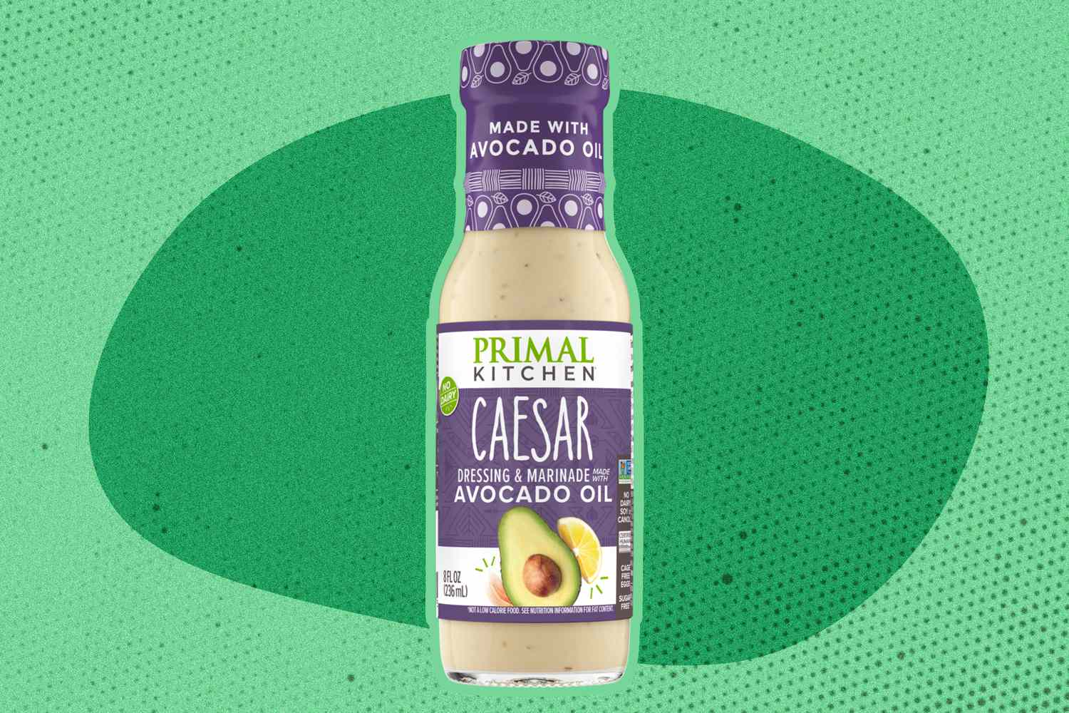 A bottle of Primal Kitchen Caesar dressing with avocado oil against a green background