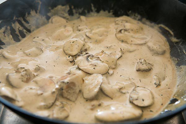 Sour cream poured in and mixed with cooking mushrooms