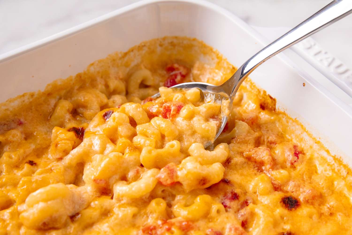 Baked macaroni and cheese in a dish with a spoon serving a portion