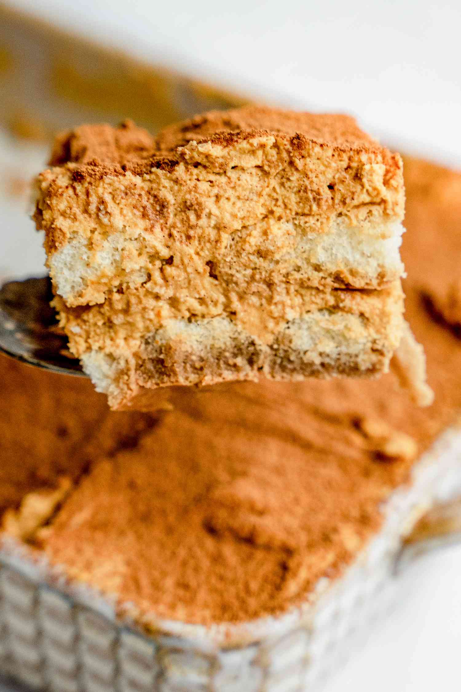 Slice of Pumpkin Tiramisu on a Serving Spatula with More in the Pan in the Background
