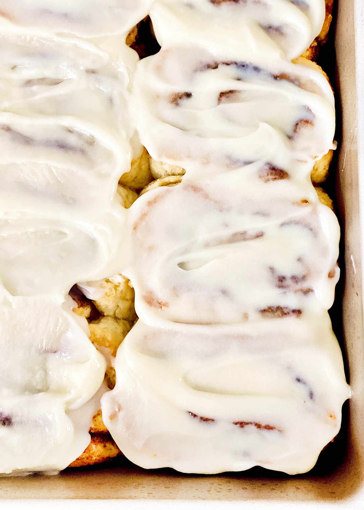 The best gluten free cinnamon rolls topped with frosting and in a pan.