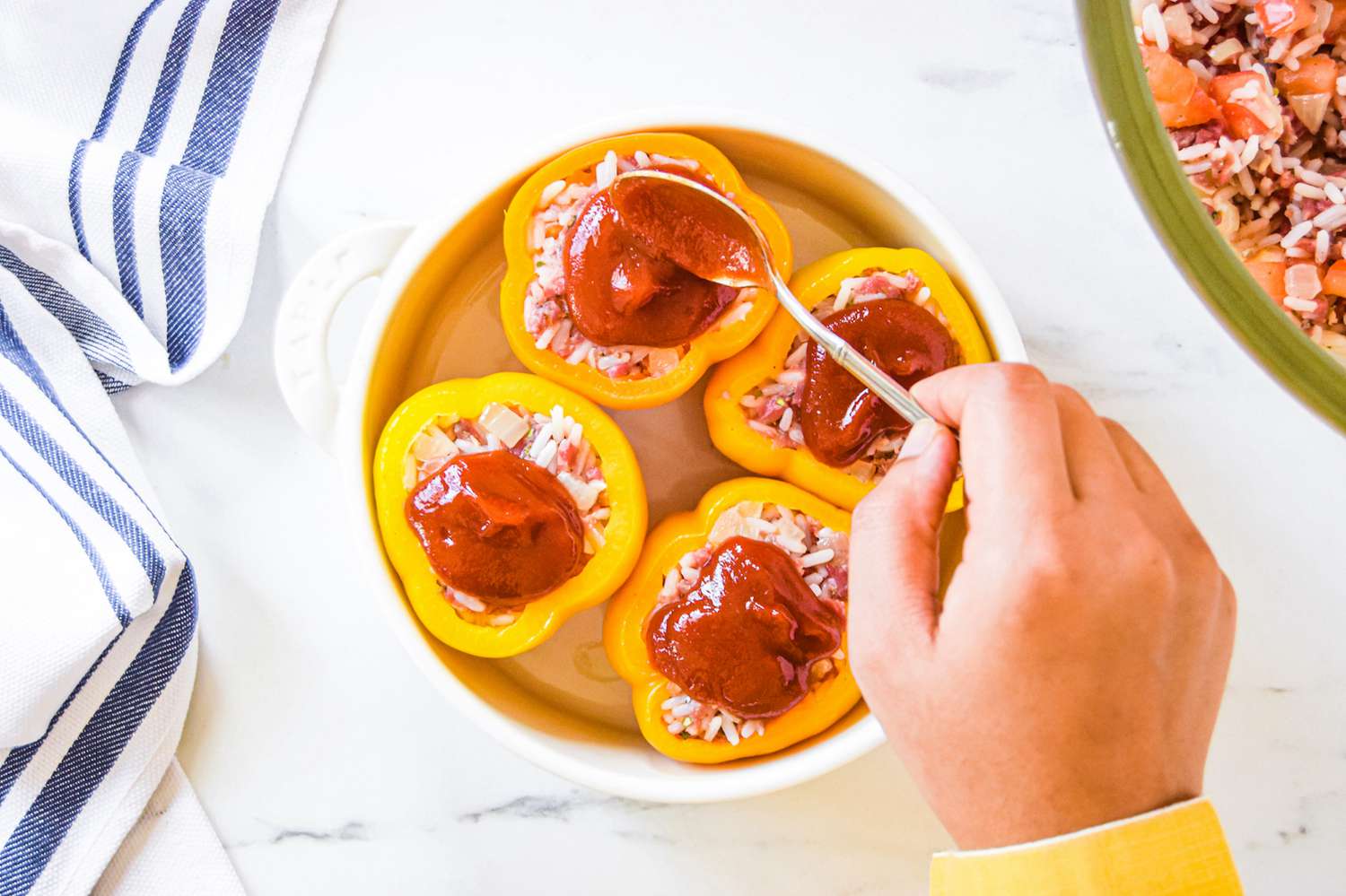 Topping stuffed yellow bell peppers with ketchup mixture.