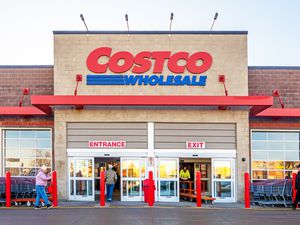 The front entrance of a Costco Wholesale store, with people walking in and out
