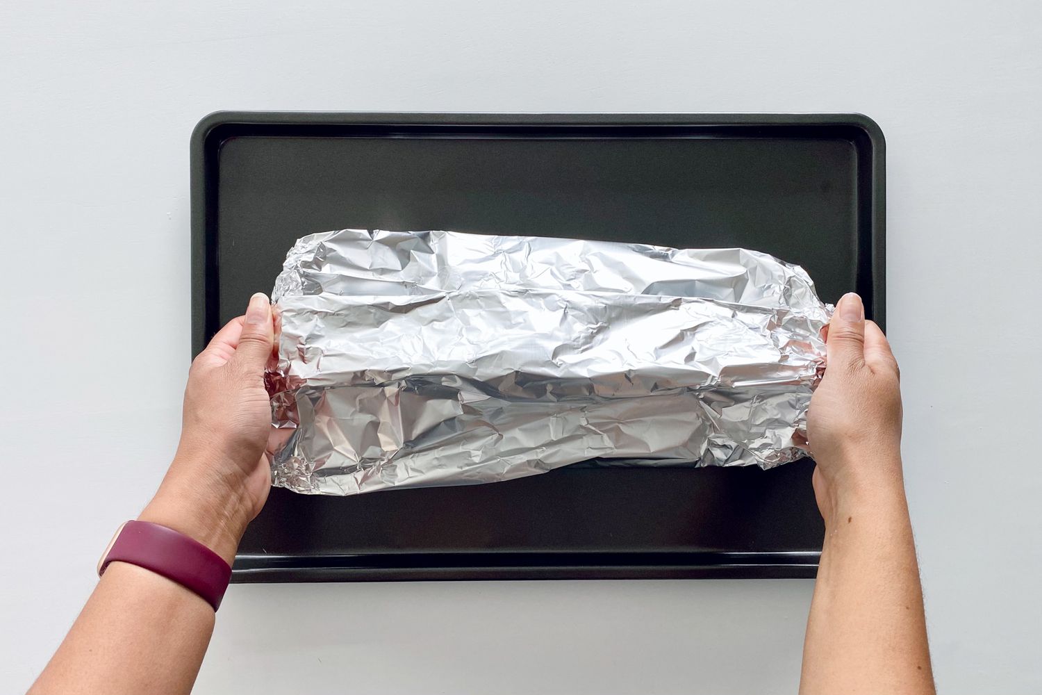 A foil packet with a salmon inside resting on a baking sheet
