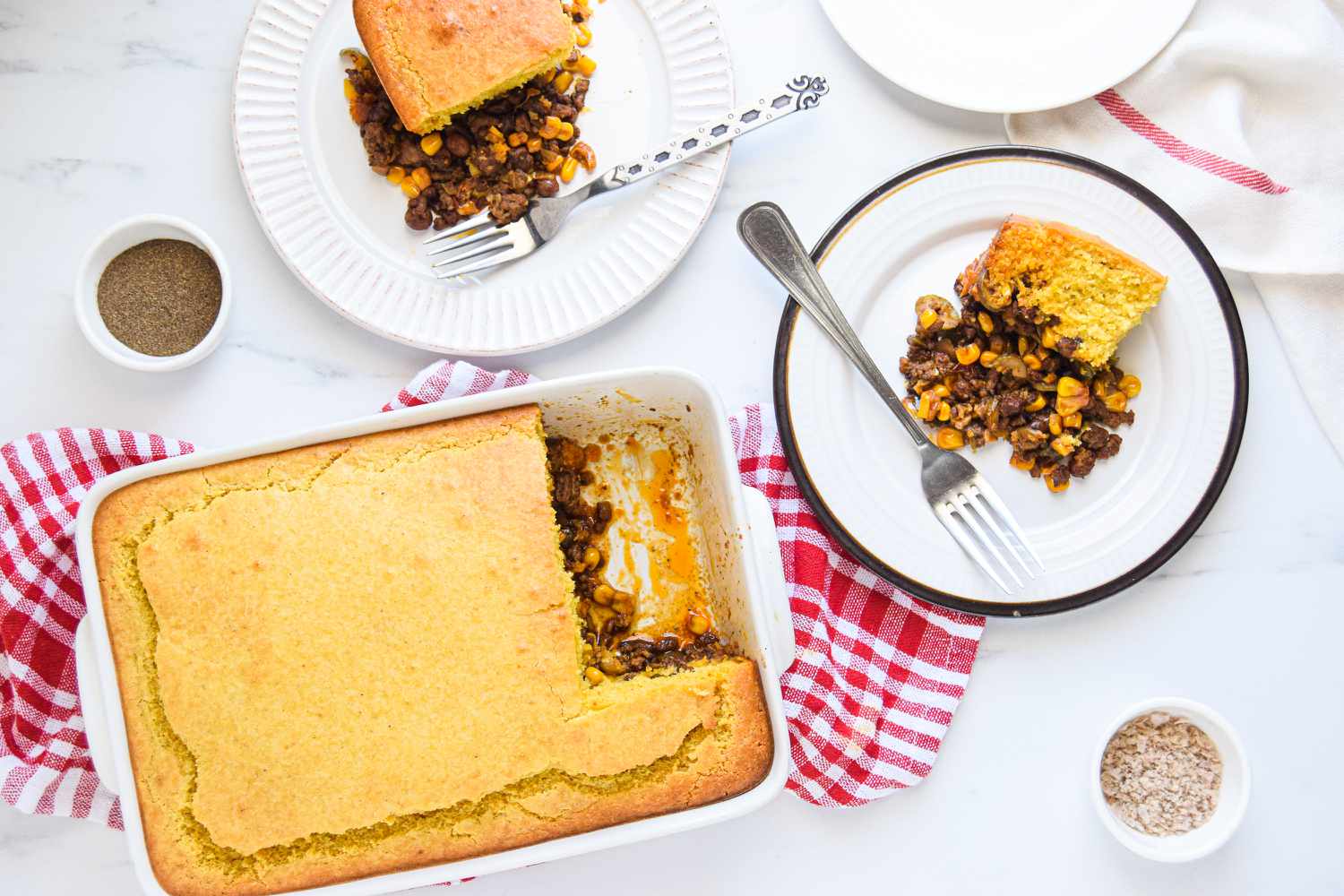 Overhead view of tamale pie with two plates of tamale pie.