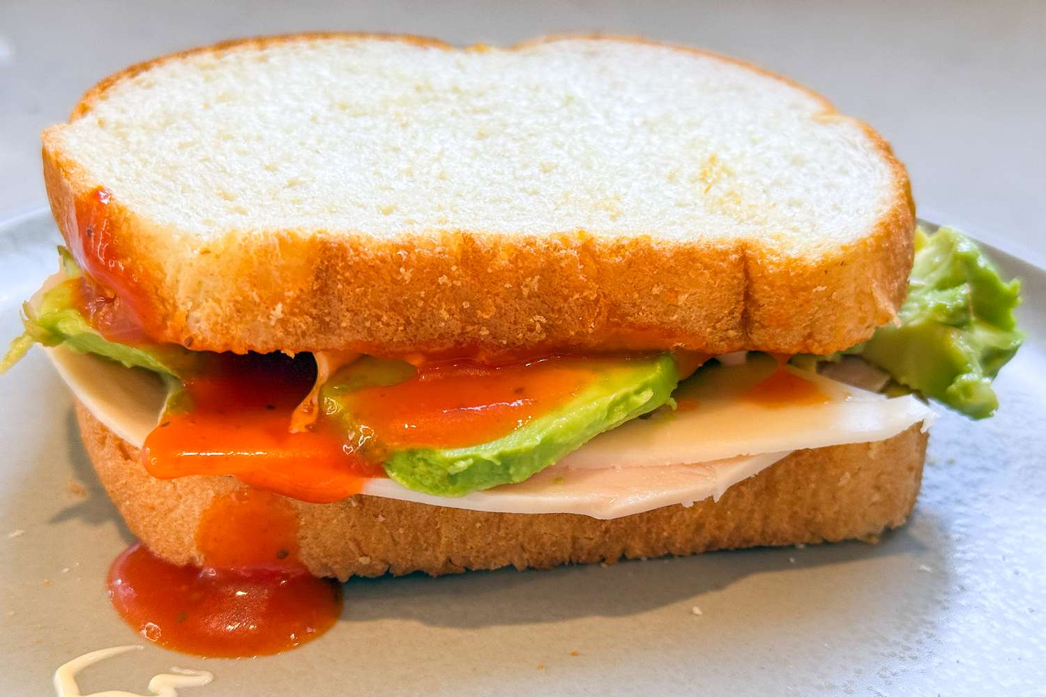 A turkey sandwich with Russian dressing running down the side