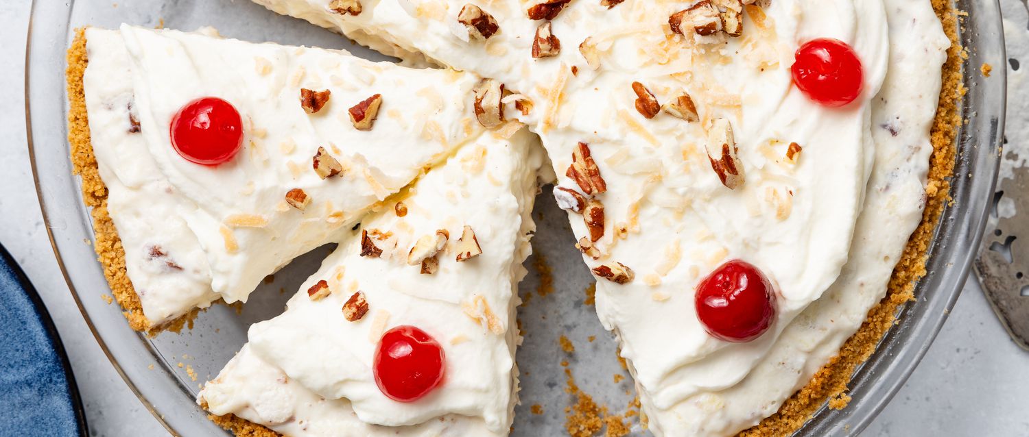 An overhead view of a sliced million dollar pie garnished with cherries