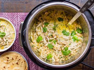 An instant pot filled with white chicken chili garnished with herbs two small bowls of similar chili and some tortillas on the side