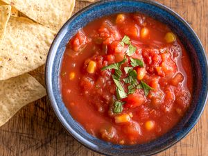 A blue bowl filled with salsa, with tortilla chips on the side