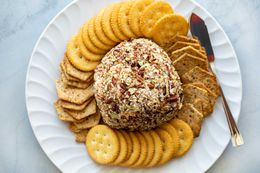 A cheese ball on a platter surrounded by crackers