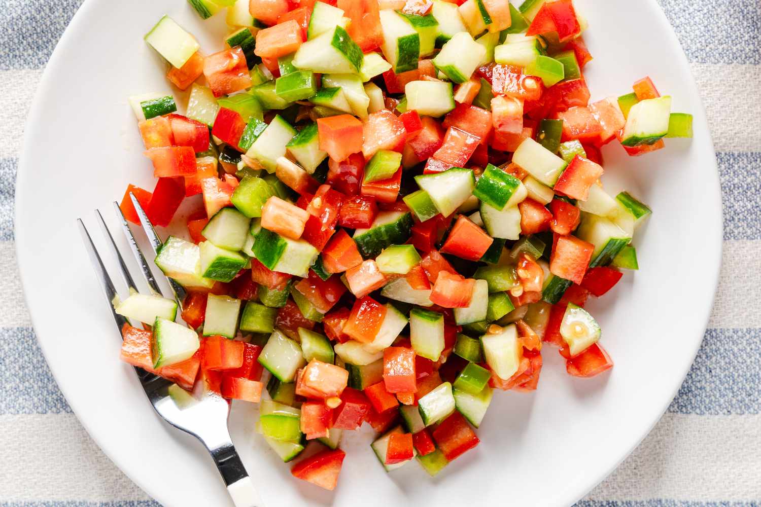 A plate of Spanish pipirrana salad with chopped vegetables and a fork