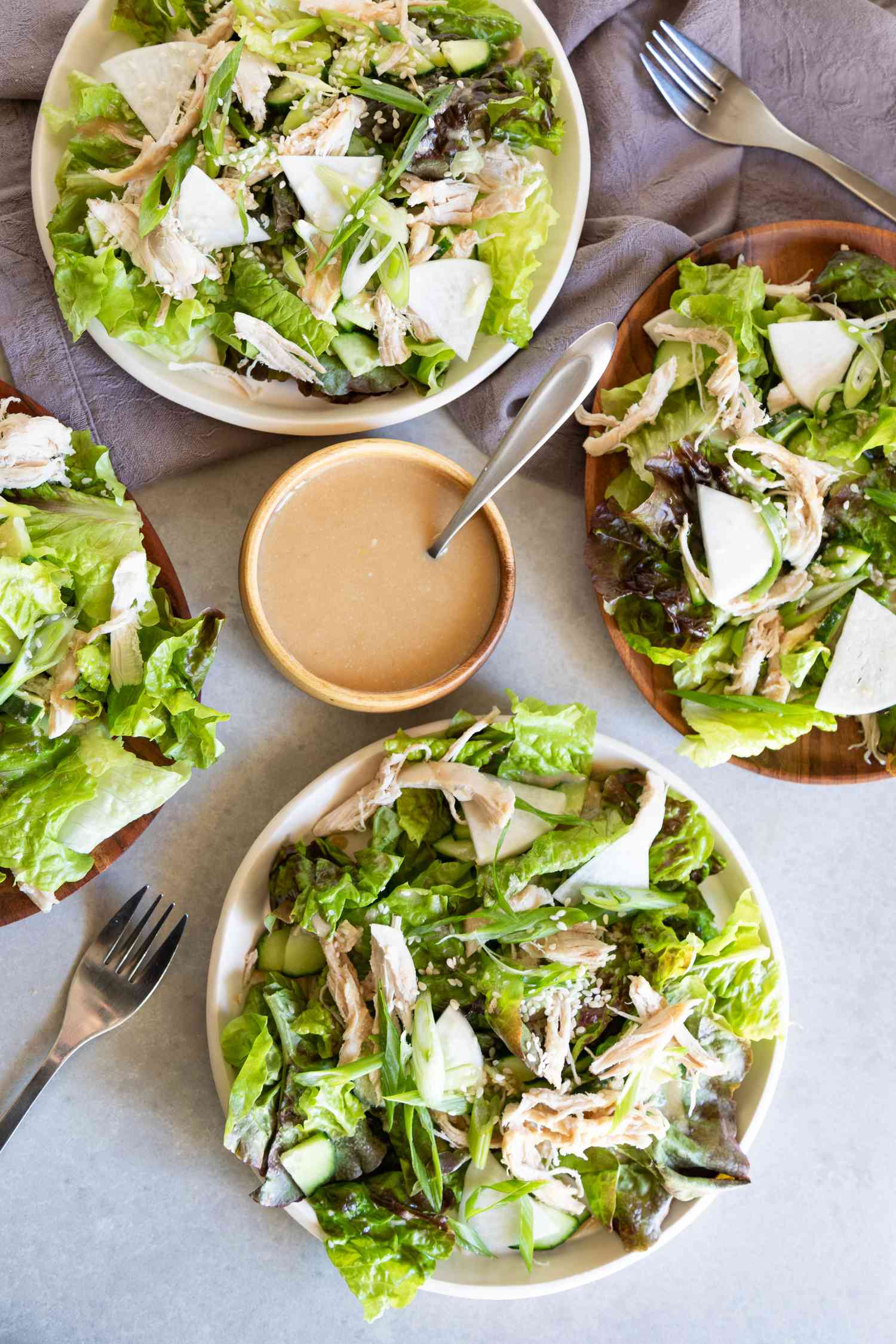 Easy sesame chicken salad in bowls with tahini dressing set in between them.