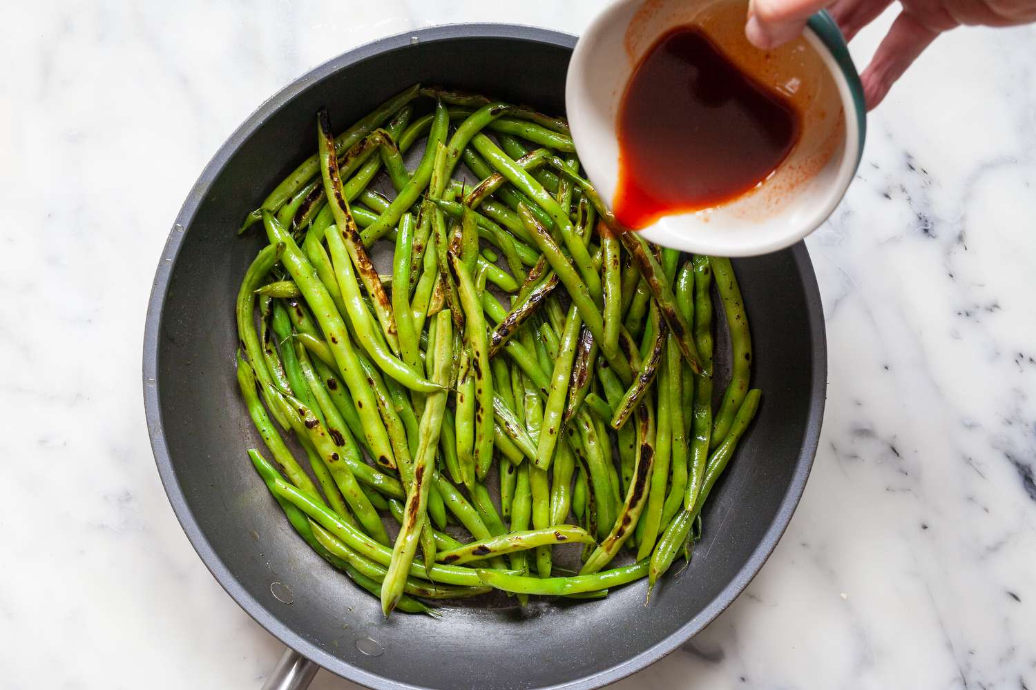 Adding the sauce for Spicy Korean Blistered Green Beans with Gochujang.