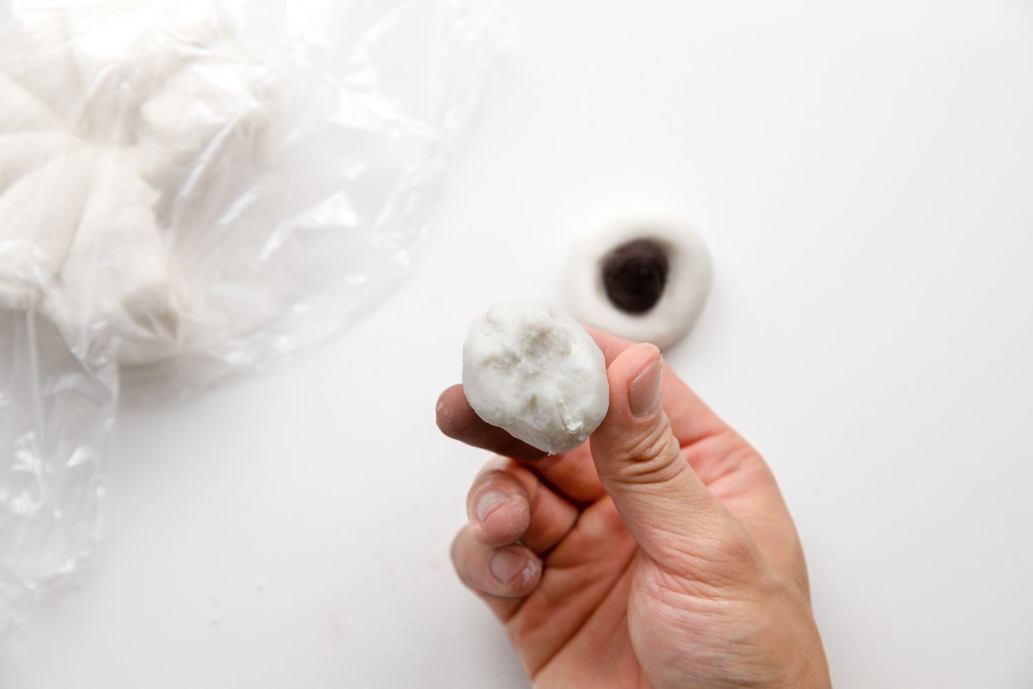 Filling the Tangyuan: Hand Showcasing a Successfully Closed Tangyuan with Red Bean Filling Inside 