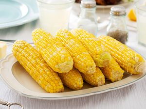 Plate of cooked corn on the cob on a table set for dining