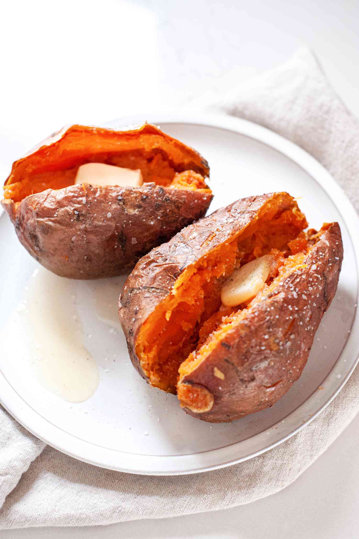 Plate with Microwave Sweet Potatoes Split in Half and Topped with a Slab of Butter and Salt 