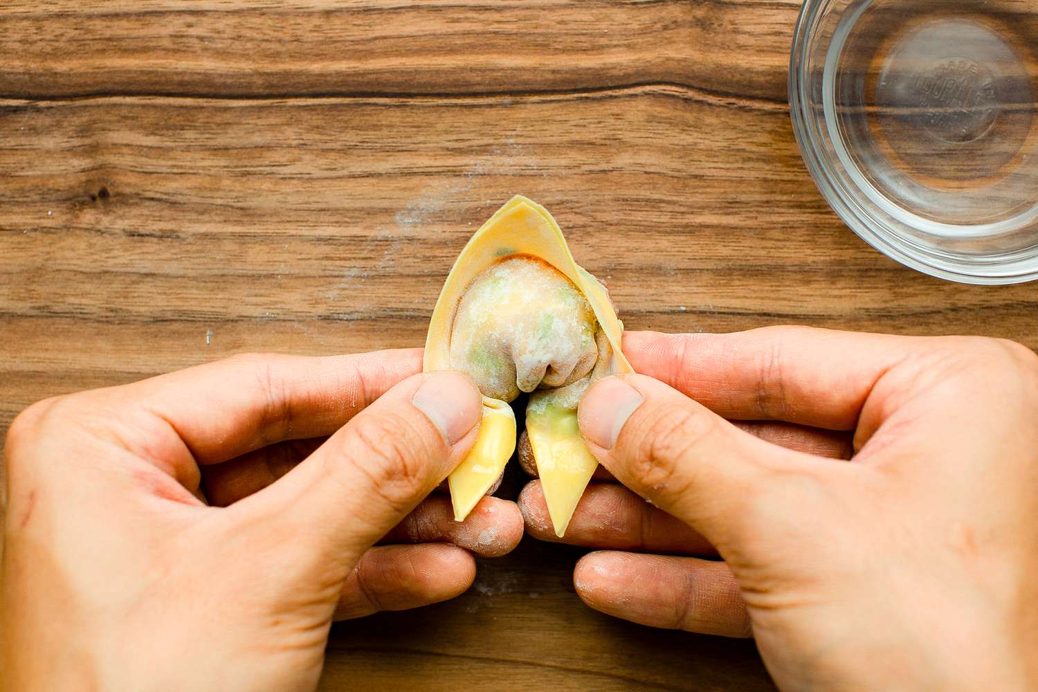 Two Corners of Folded Dumpling Wrapper Brought to Center Forming a Filling Bubble. Corners Brushed with Water.