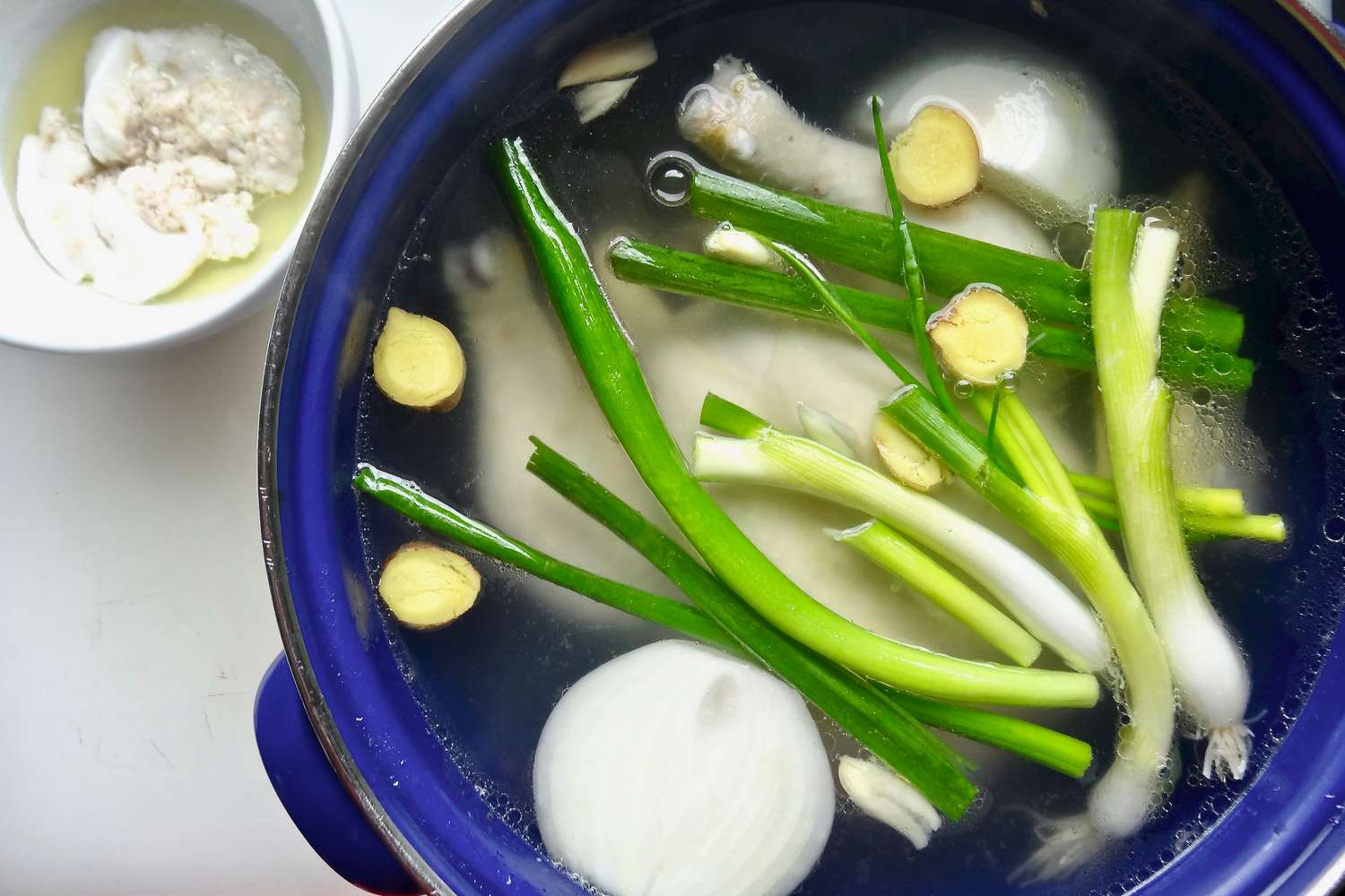 Aromatics added to the pot with the chicken inside to make easy pork wontons in homemade chicken broth.