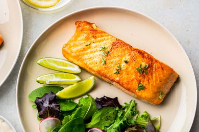 Salmon fillet on a plate with a side salad and lime slices