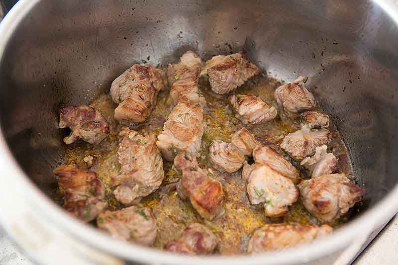 Browned lamb shoulder pieces in pan prepared for lamb stew