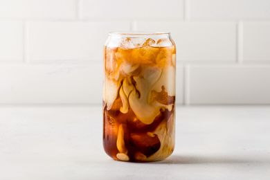 Cold brew mixed with milk in a tall class on a white countertop