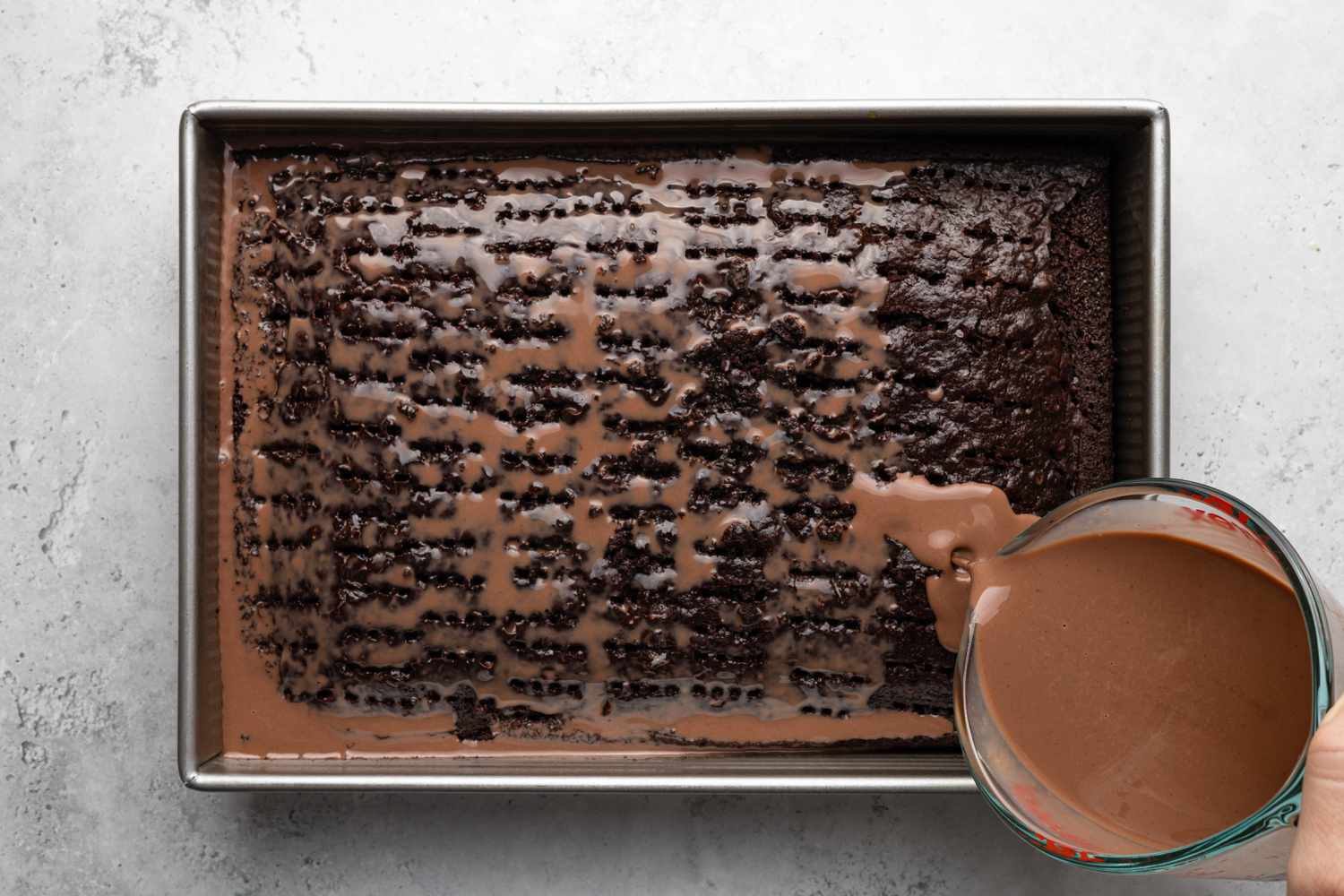 Chocolate Milk Mixture Poured onto Chocolate Tres Leches Cake after It Was Pierced with a Fork