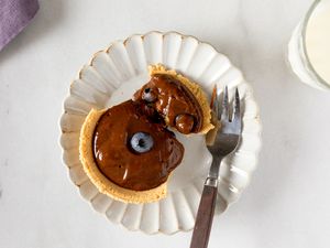 Mini chocolate pudding pie on a white plate with a fork topped with blueberries