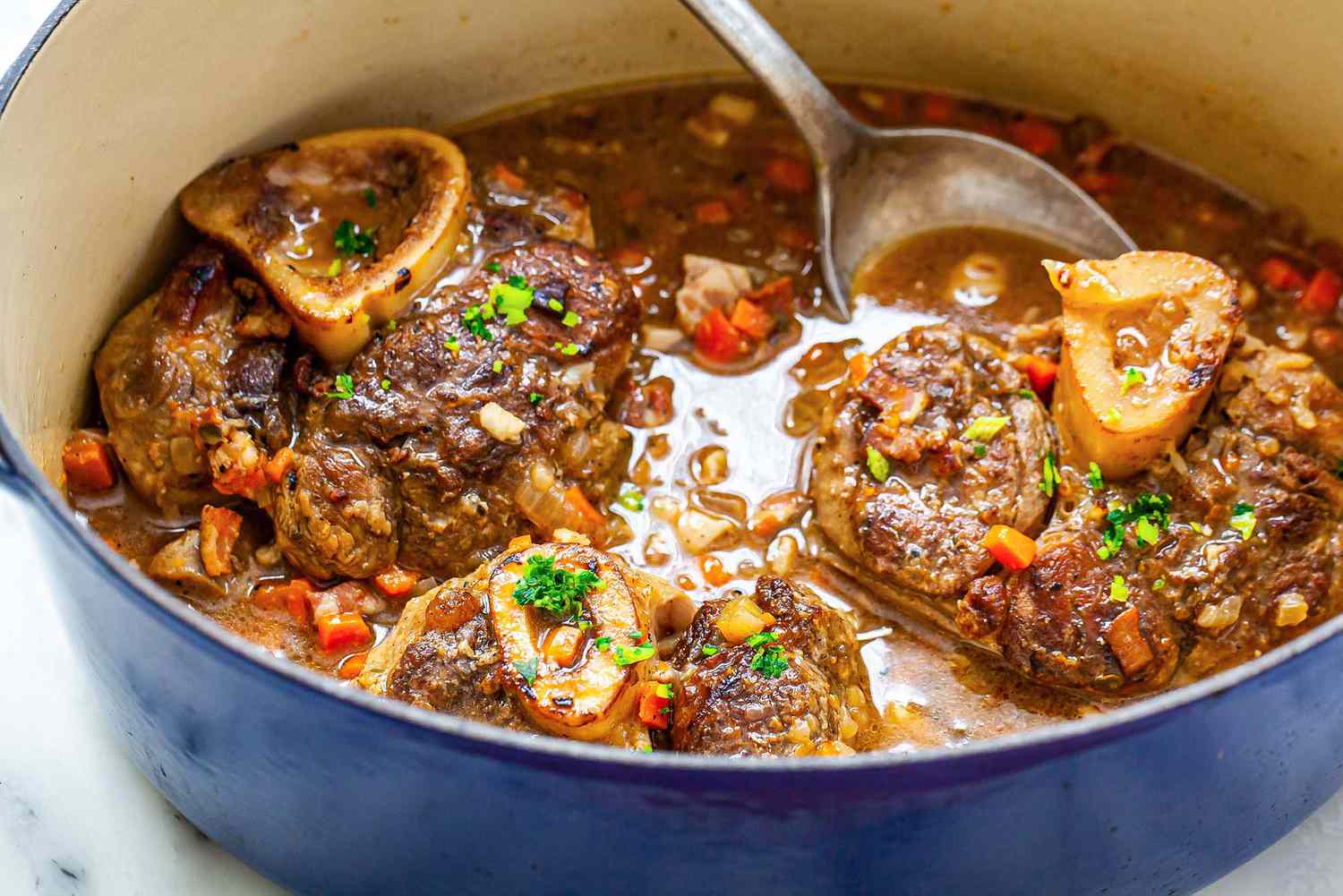 osco busco in a dutch oven with a serving spoon