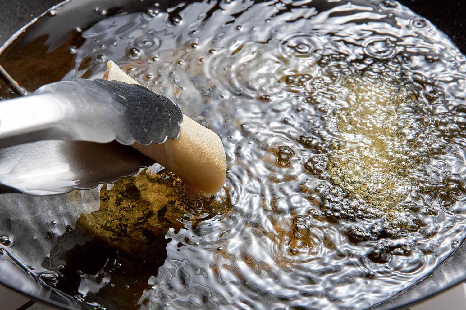 Tongs Carefully Placing Cut Lumpia Into the Hot Oil for Filipino Lumpia Recipe