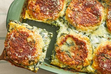 A baked spinach and cheese lasagna being served from a casserole dish
