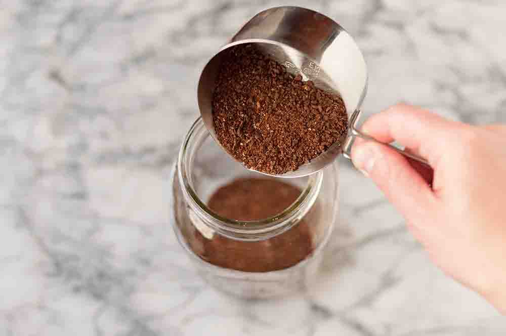 Coffee grounds being poured into a jar 