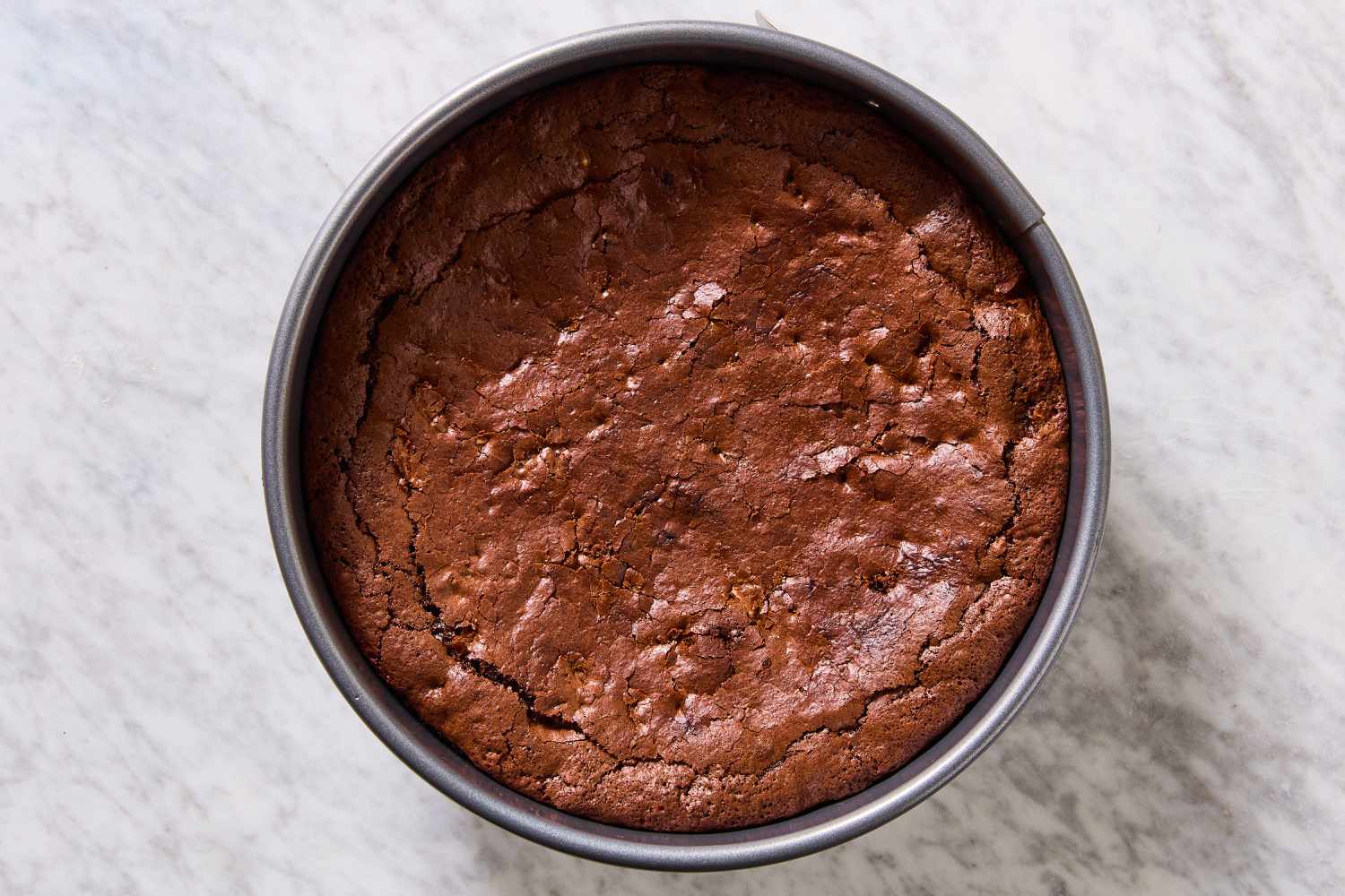 Overhead view of a springform pan showing the baked brownie batter after cooling and deflating for Mississippi Mud Pie recipe