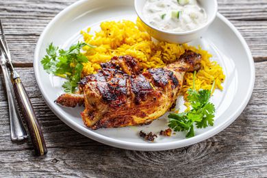 Grilled Tandoori Chicken with Turmeric Rice on Plate Next to Bowl of Raita