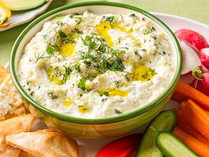 zucchini dip in a bowl on a plate with sliced vegetables
