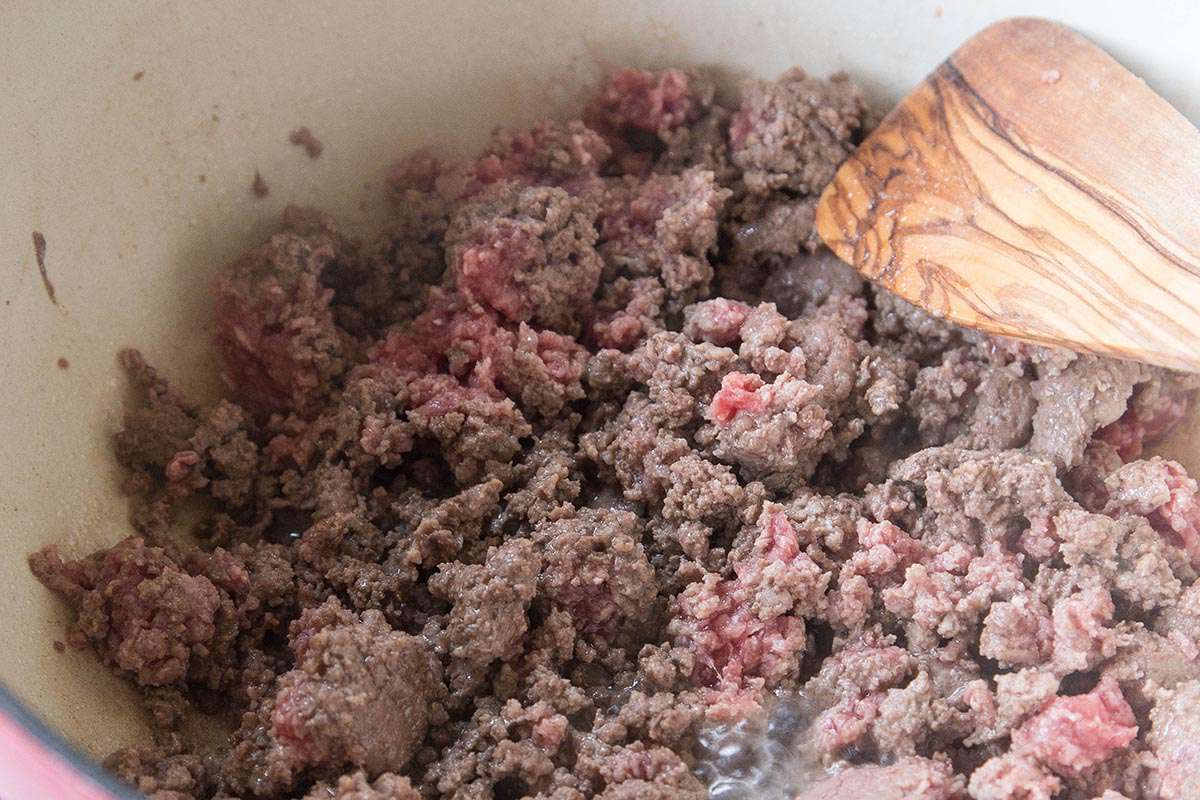 Ground beef cooking and being stirred in a Dutch oven