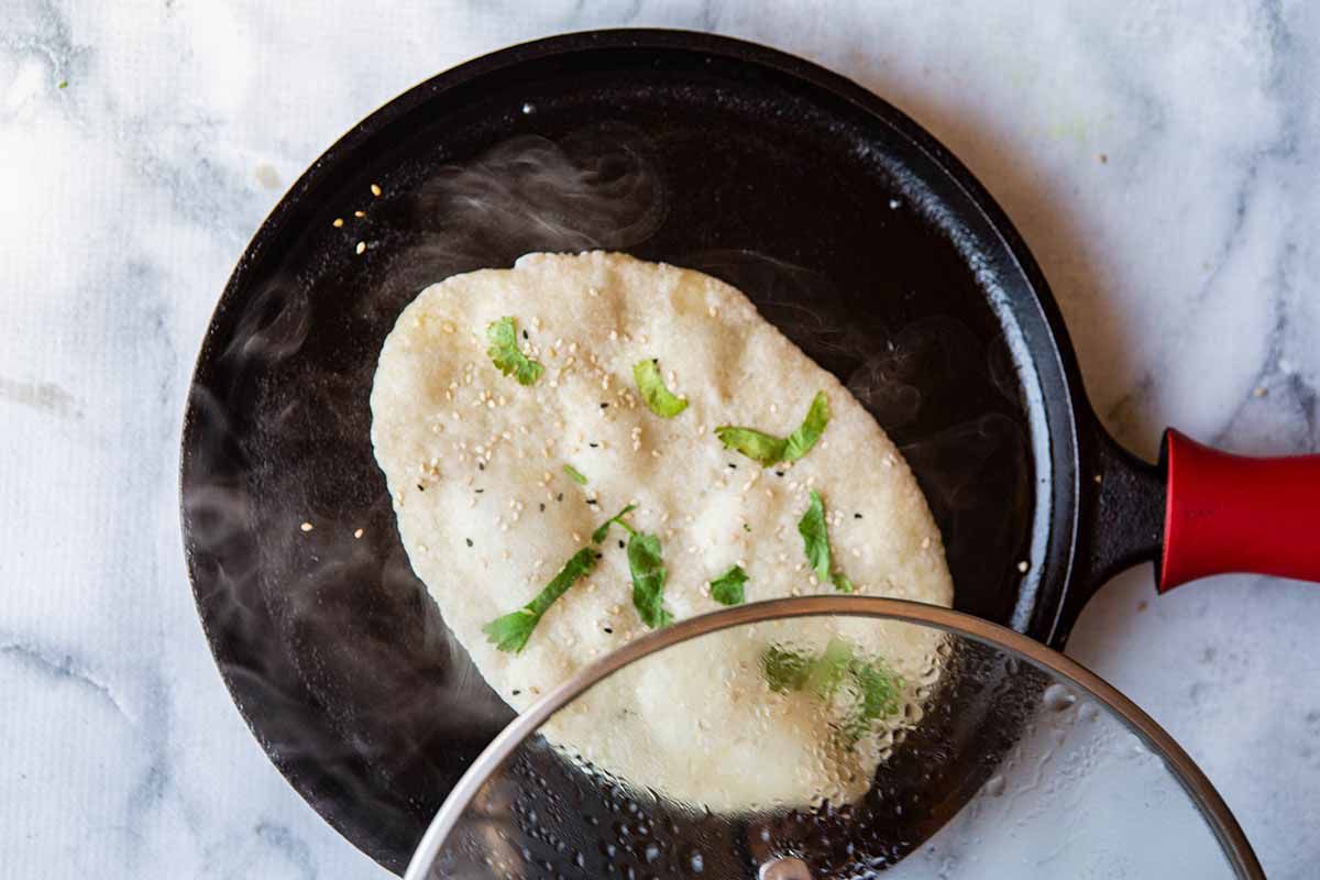 Indian Flatbread - dough on skillet wih lid lifting off of skillet