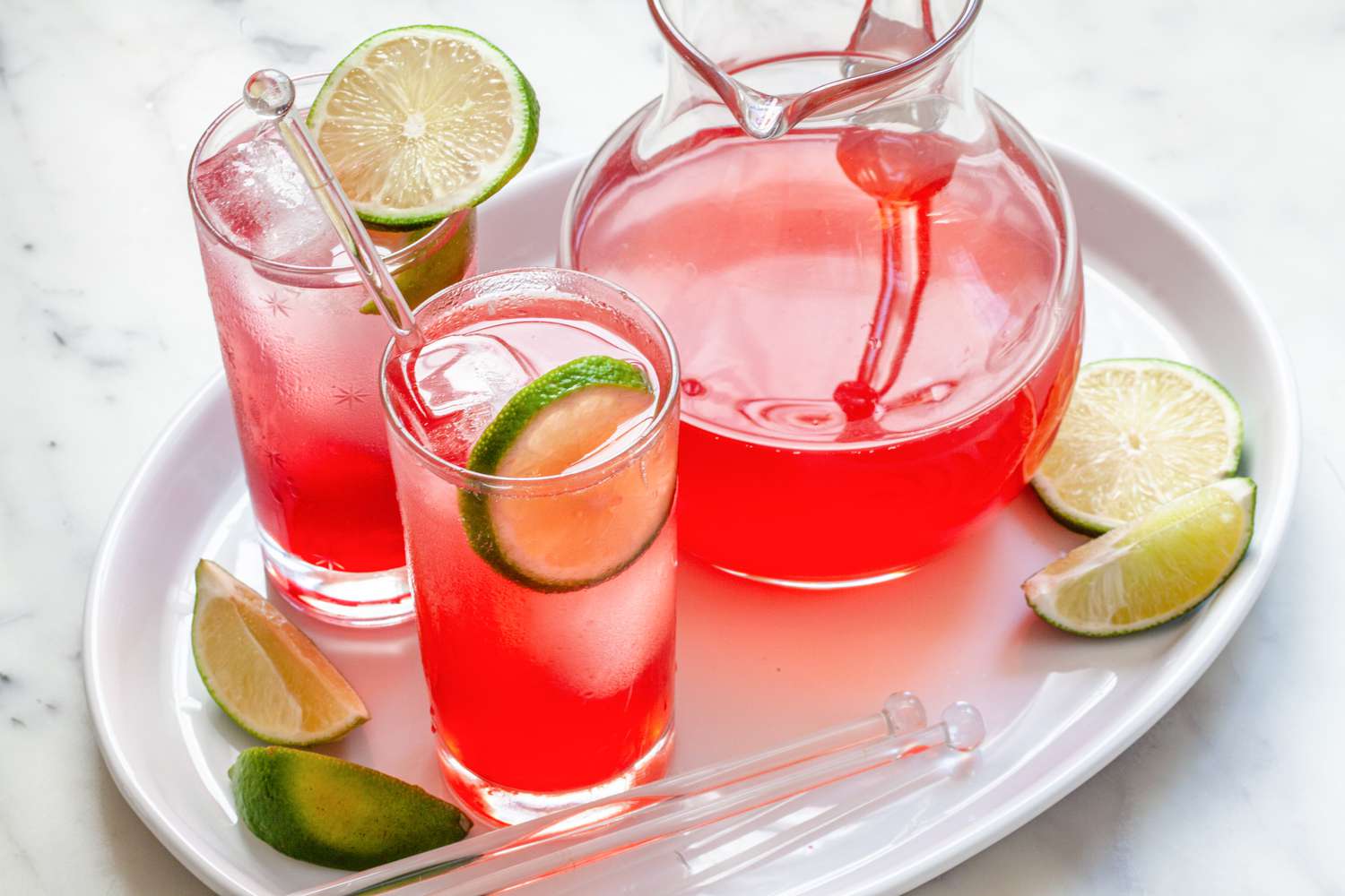 Best ever raspberry lime rickey in two glasses with a pitcher next to it.