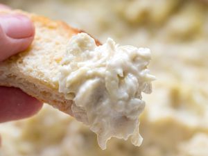 Hand Holding a Piece of Toast With Some Quick and Easy Artichoke Dip on It 