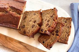 A loaf of rum raisin banana bread with four slices cut off and laying next to each other.