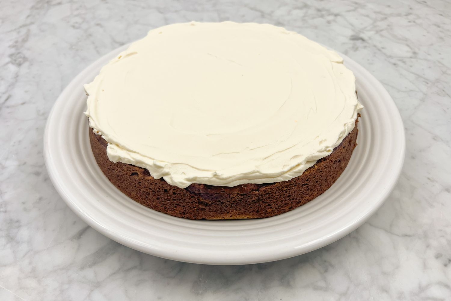 Frosted pumpkin cake on a plate marble surface