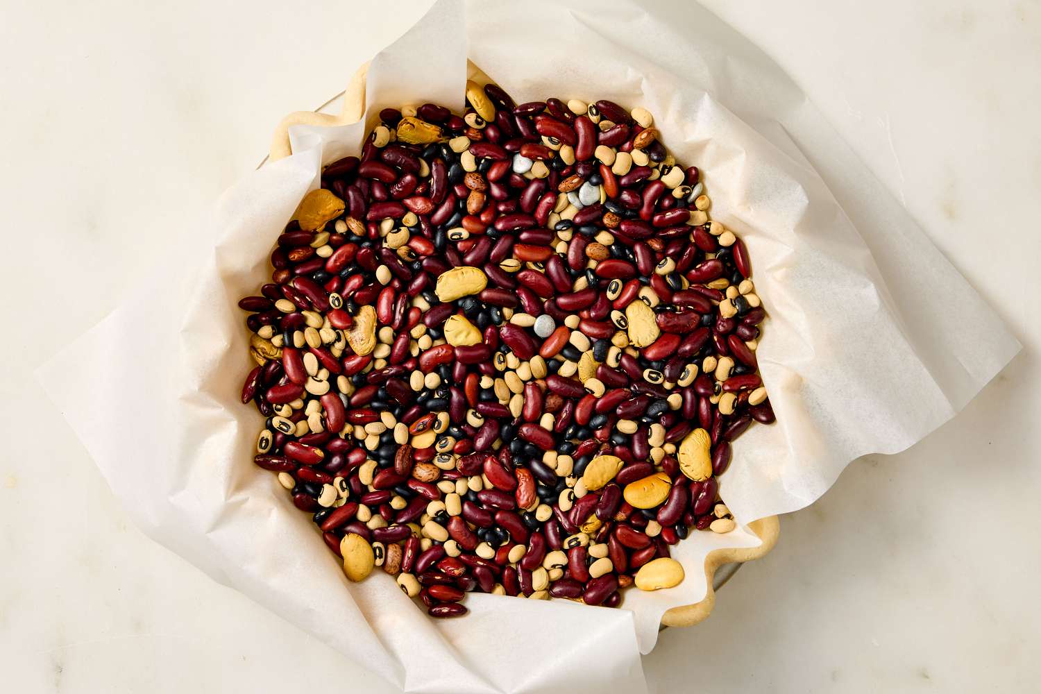 pie dough in a shell with parchment and dry beans added