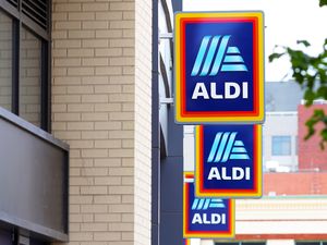 Three Aldi store signs on the exterior of a building visible in an urban setting with brick and glass details
