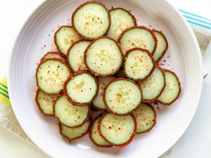 Round cucumber slices sprinkled with Tajin seasoning arranged in a bowl