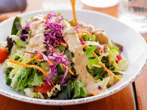 Close up of a salad with dressing being poured on it