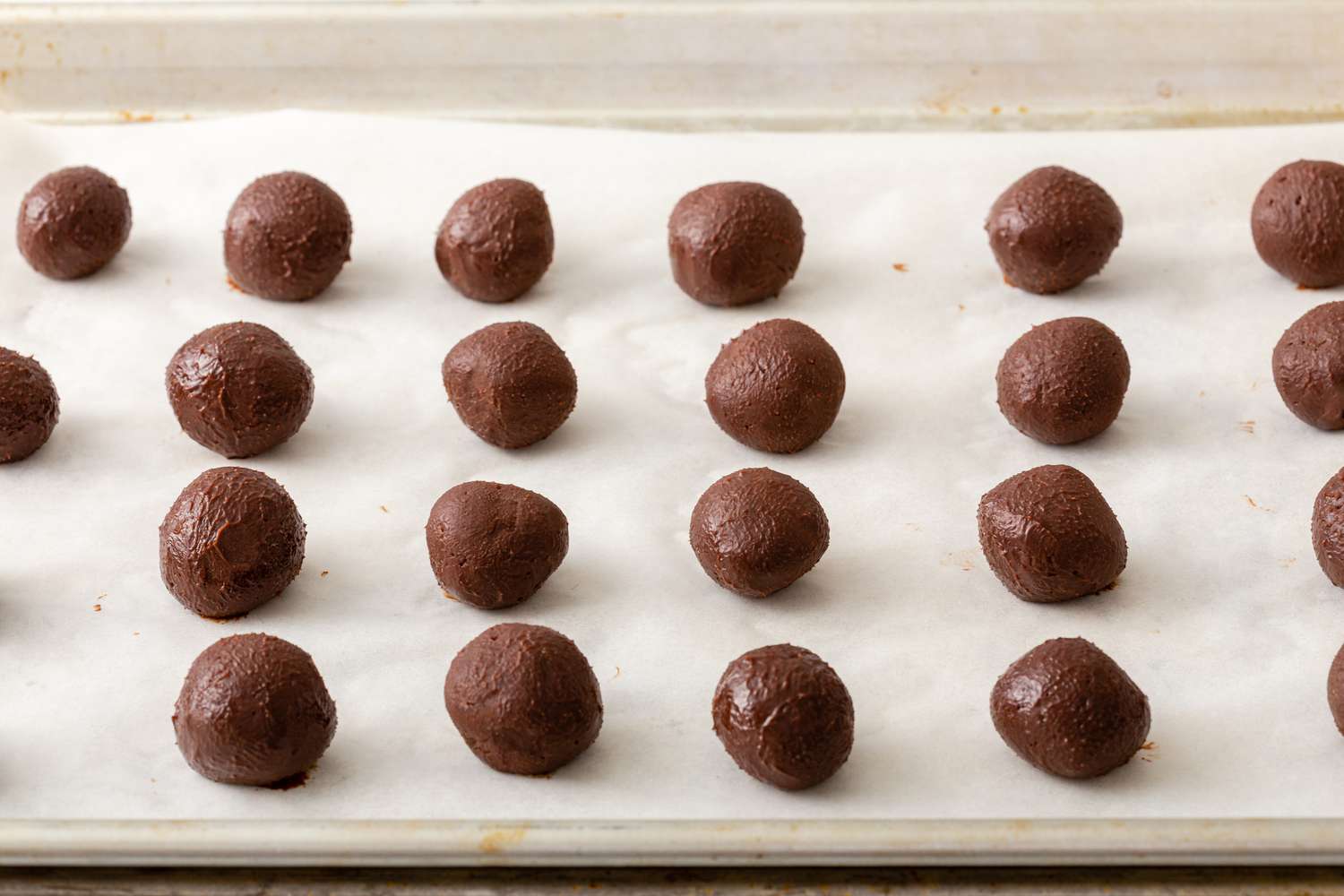 Balls of ganache set on a parchment lined baking sheet for a chocolate truffle recipe.