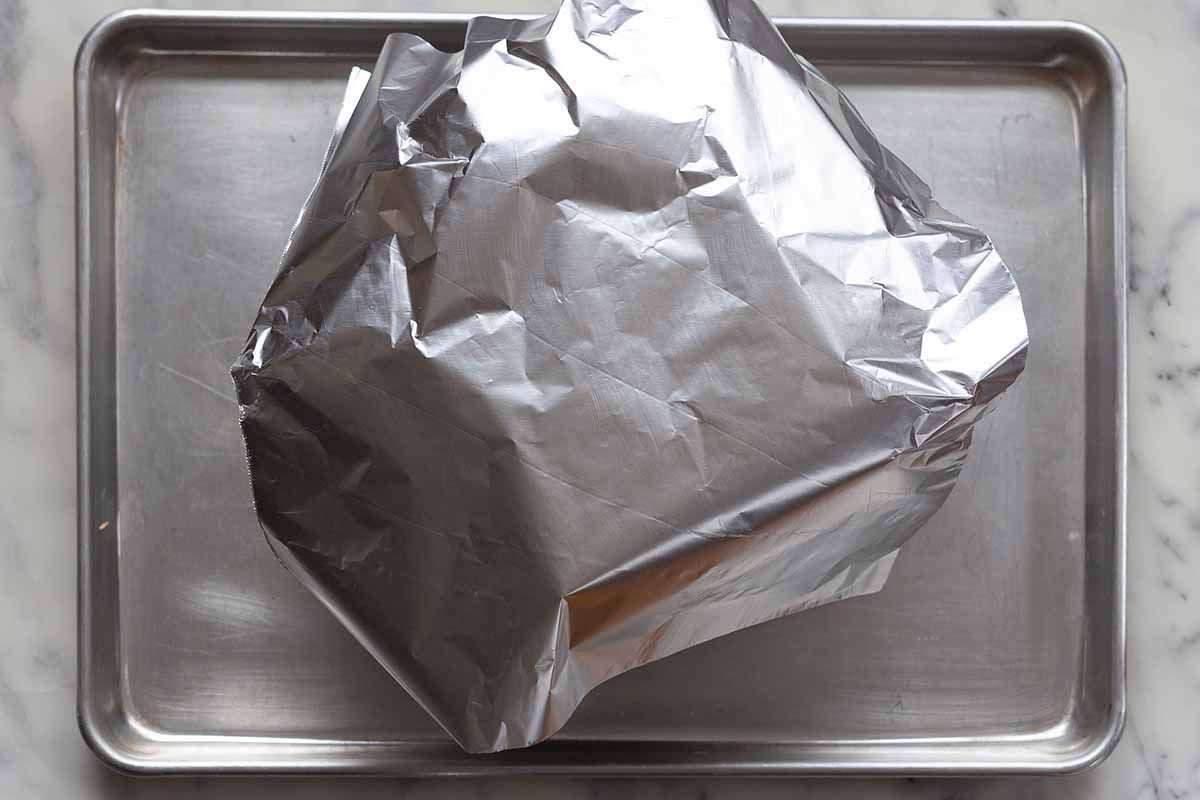 Panettone tented with foil on a baking sheet