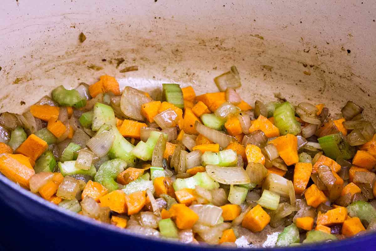 Onions, carrots, and celery being sautéd in a Dutch oven 